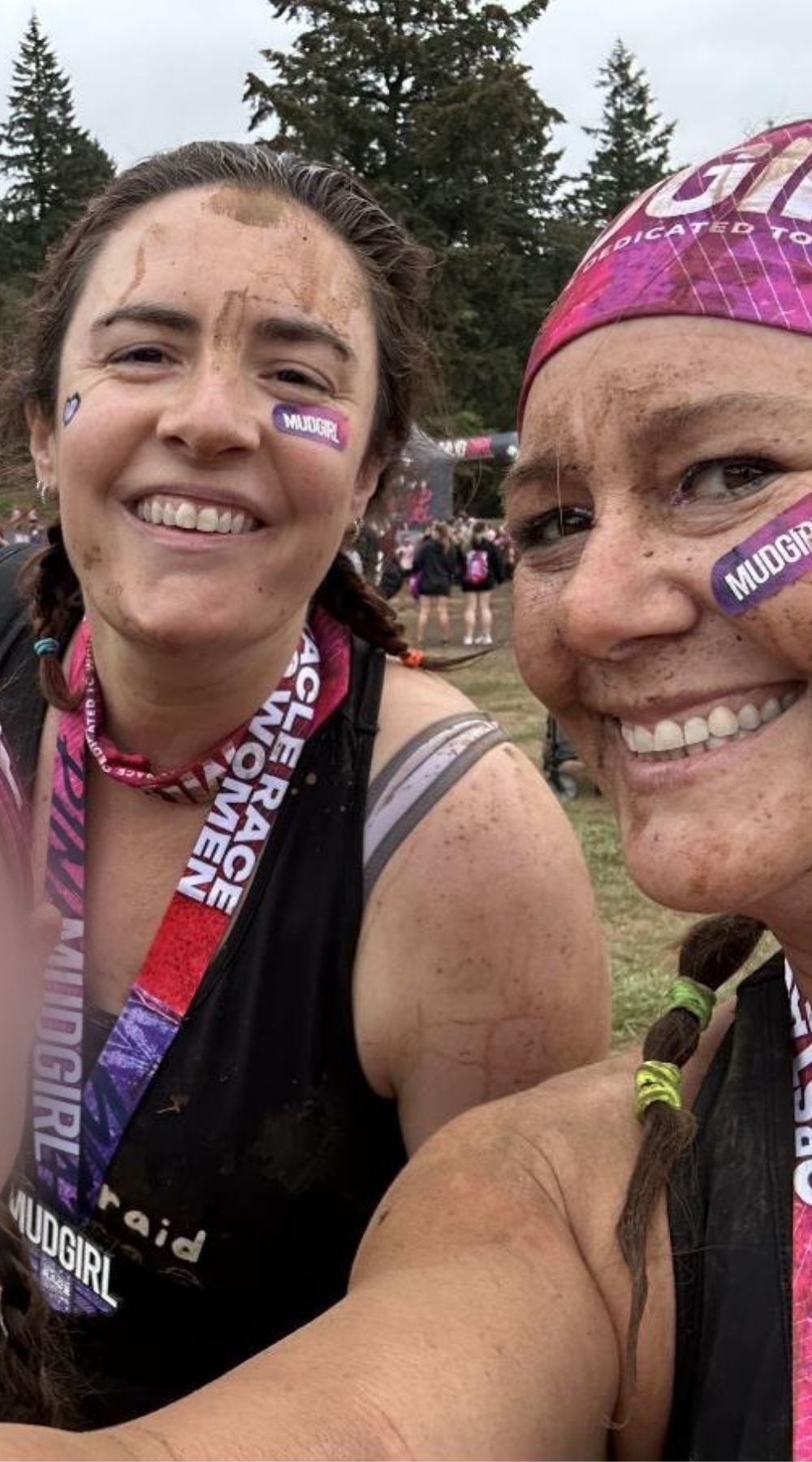 Jess Perkz, on the left, with her cousin after a Mud Girl obstacle race, both covered in mud and laughing.